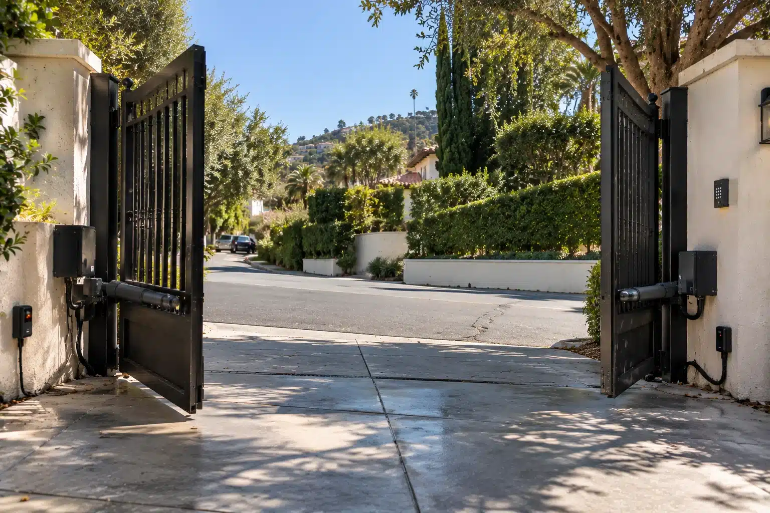 Gate opener arm and photo eye safety sensor on a Beverly Hills driveway gate
